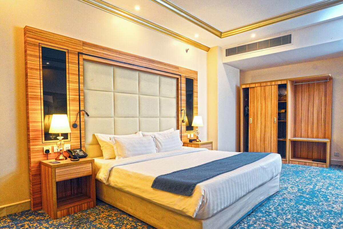 Une chambre d’hôtel avec un grand lit, deux tables de chevet avec des lampes, une armoire et un miroir.
