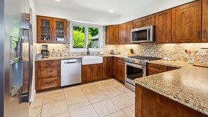 Une cuisine moderne avec des meubles en bois, des appareils en acier inoxydable et un plan de travail en granit.