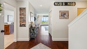 Un couloir avec un plancher en bois, un tapis, une pancarte d’accueil, une pancarte indiquant « NUBS NOB » et une photo encadrée accrochée au mur.