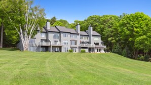Une grande maison à plusieurs étages, avec une pelouse bien entretenue à l’avant.