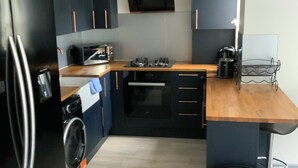 Une cuisine compacte équipée d’un lave-linge, d’un four à micro-ondes et d’un évier.