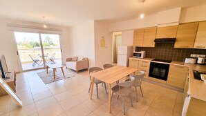 Een moderne keuken met houten kastjes, een eettafel met stoelen, en een zithoek met een bank.