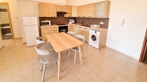 Een moderne keuken met houten kastjes, een magnetron, een spoelbak, een vaatwasser en een tafel met stoelen.
