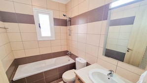 Een moderne badkamer met een badkuip, toilet, wastafel en spiegel.