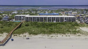 Ein Hotel direkt am Strand mit einem langen, schmalen Gebäude, einem Steg und einem Sandstrand.
