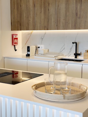 A modern kitchen with a marble backsplash, a black faucet, and a woven tray with glasses.