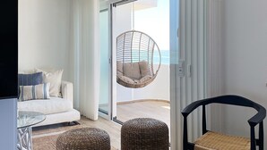 A modern bedroom with a bed, a hanging chair, a sofa, and wicker ottomans. - Front Sea Apartment Albufeira (Albufeira)