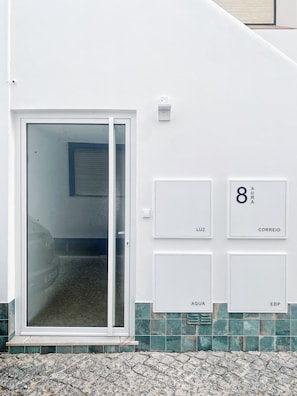 A white building with a glass door and numbered mailboxes labeled 'Luz', 'Aqua', '8', 'Correio', and 'EDP'.