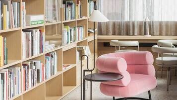 A library with bookshelves, a pink armchair, and a round table.