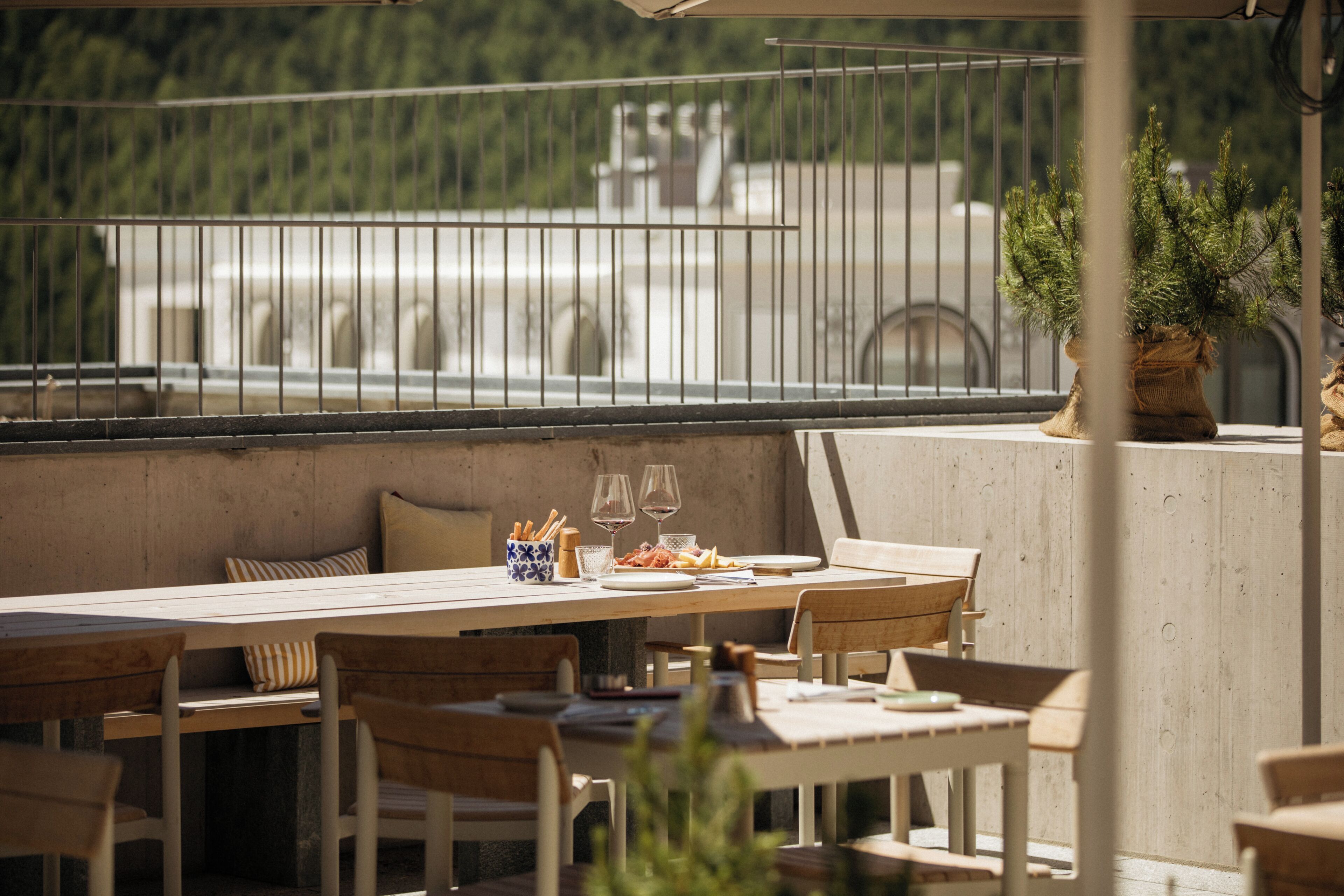 A terrace with a dining table set for two, surrounded by wooden chairs.