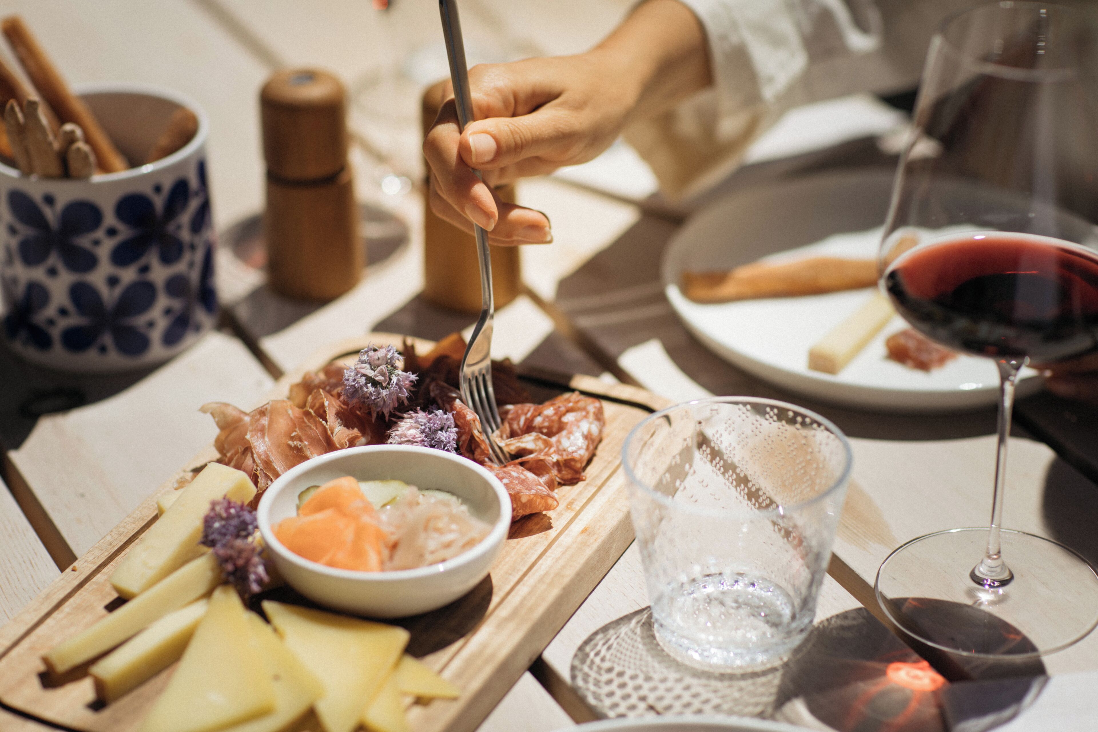 Une planche en bois garnie de fromage, de charcuteries et d’un bol de légumes marinés.