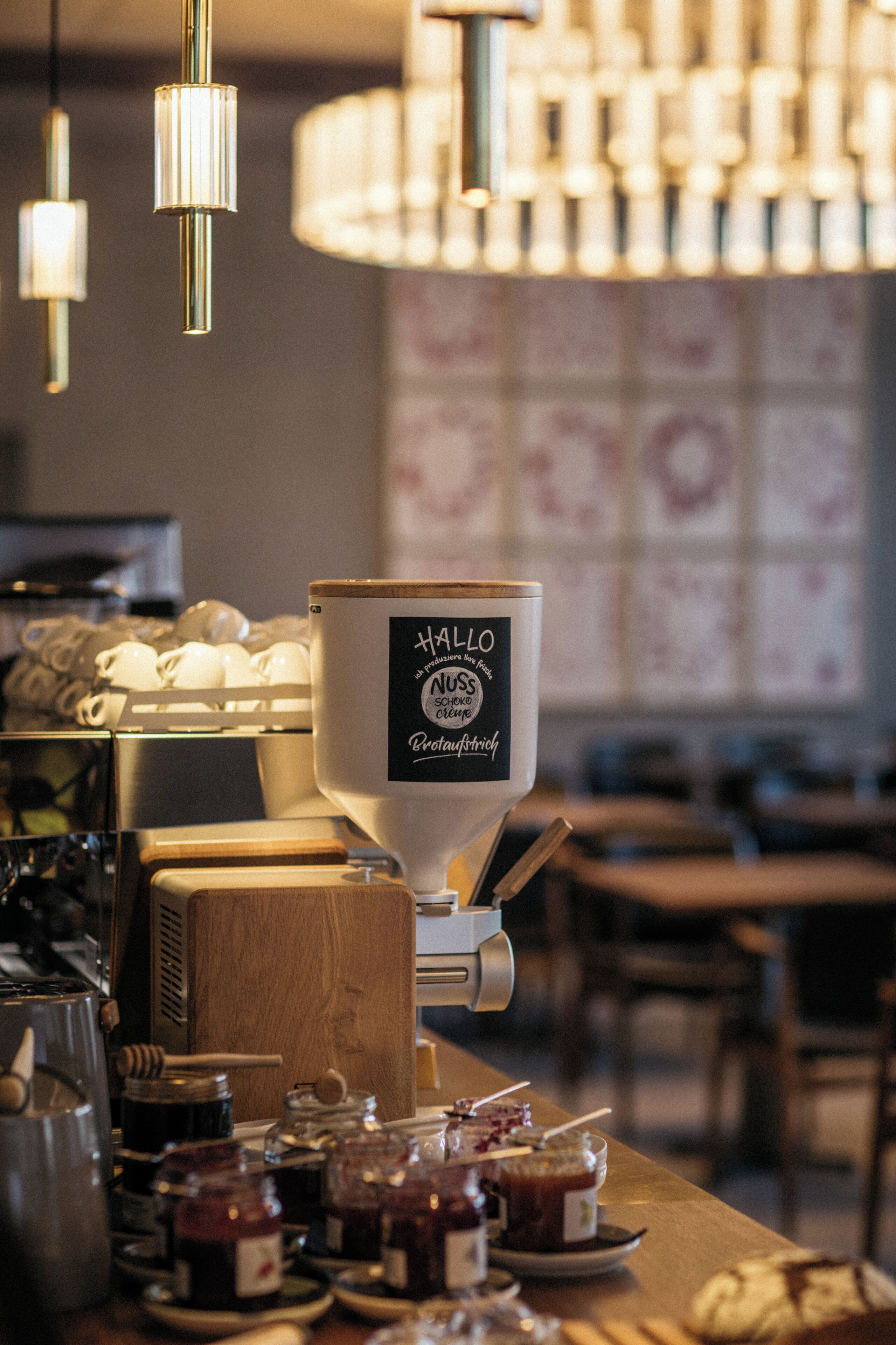 A coffee machine with a label, jars of honey, and a wooden counter.