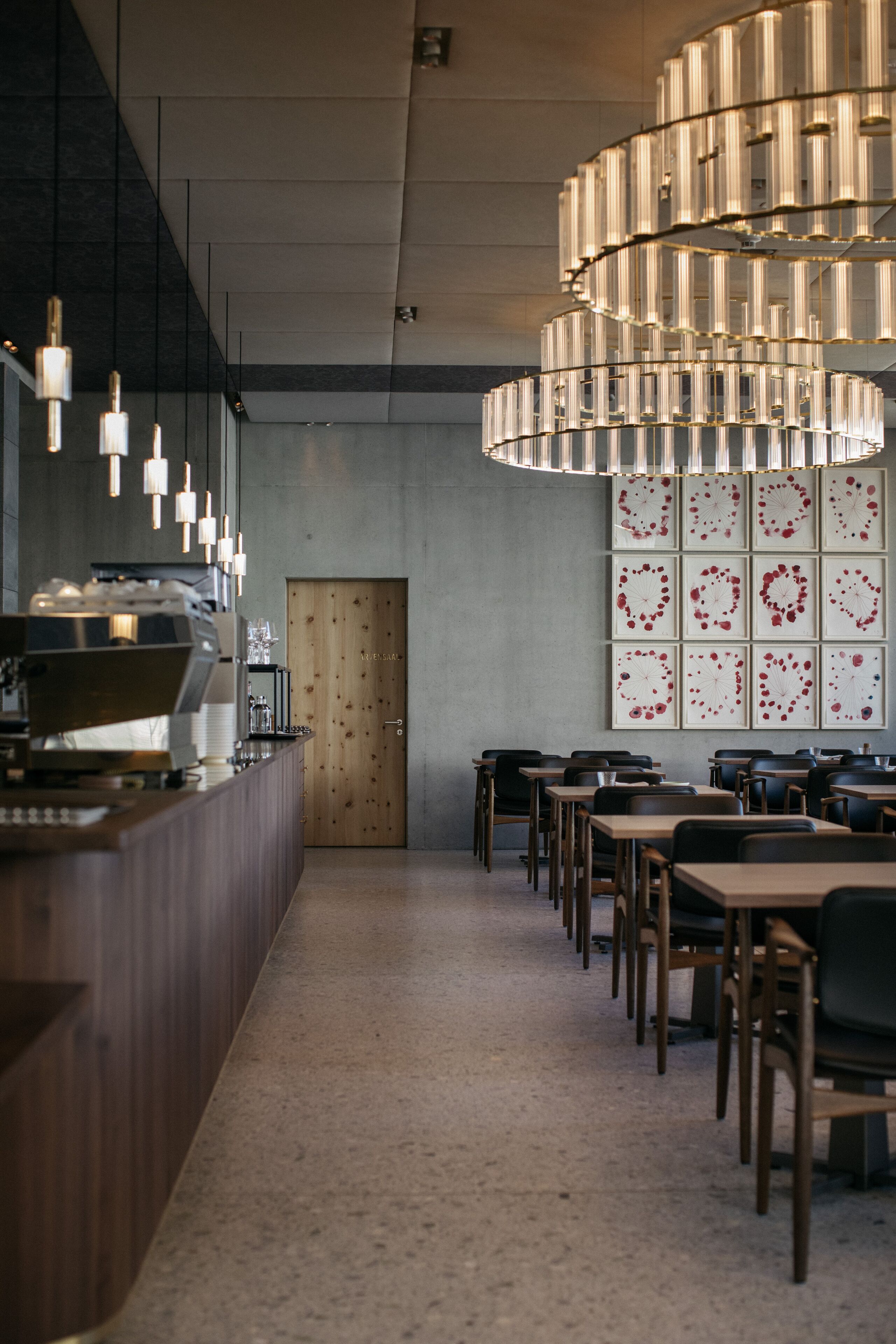 Ein modernes Interieur mit Barbereich, Holztischen und einer einzigartigen Deckenleuchte.