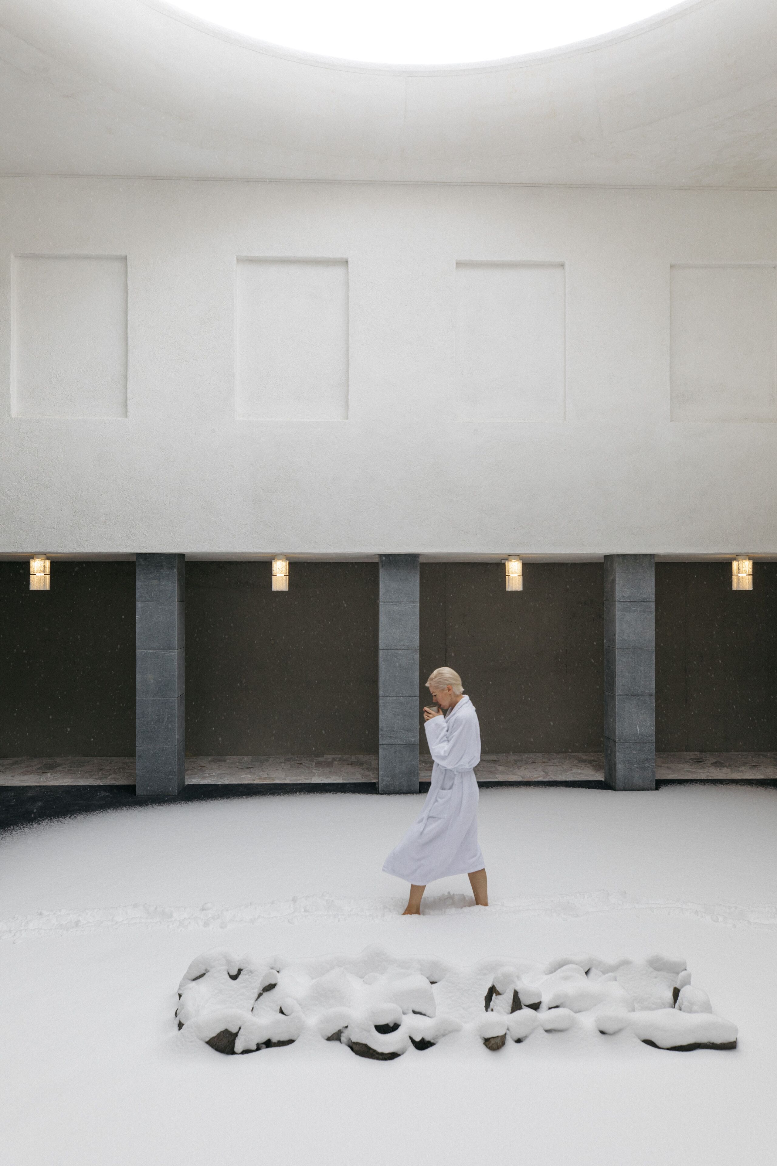 A spacious indoor area with a high ceiling, stone columns, and recessed lighting.