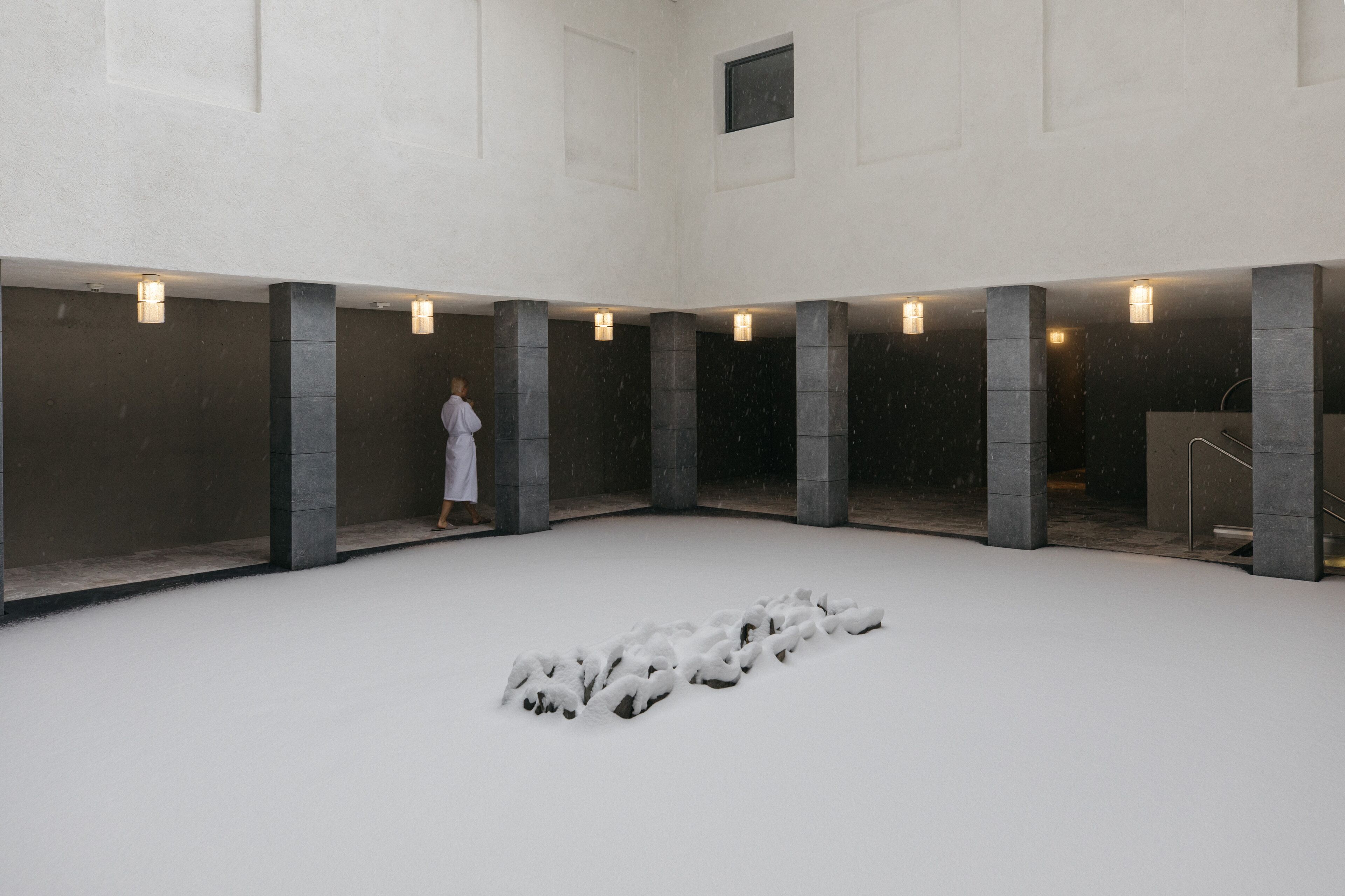 A spacious indoor area with a central snow-covered feature, surrounded by pillars and recessed lighting.