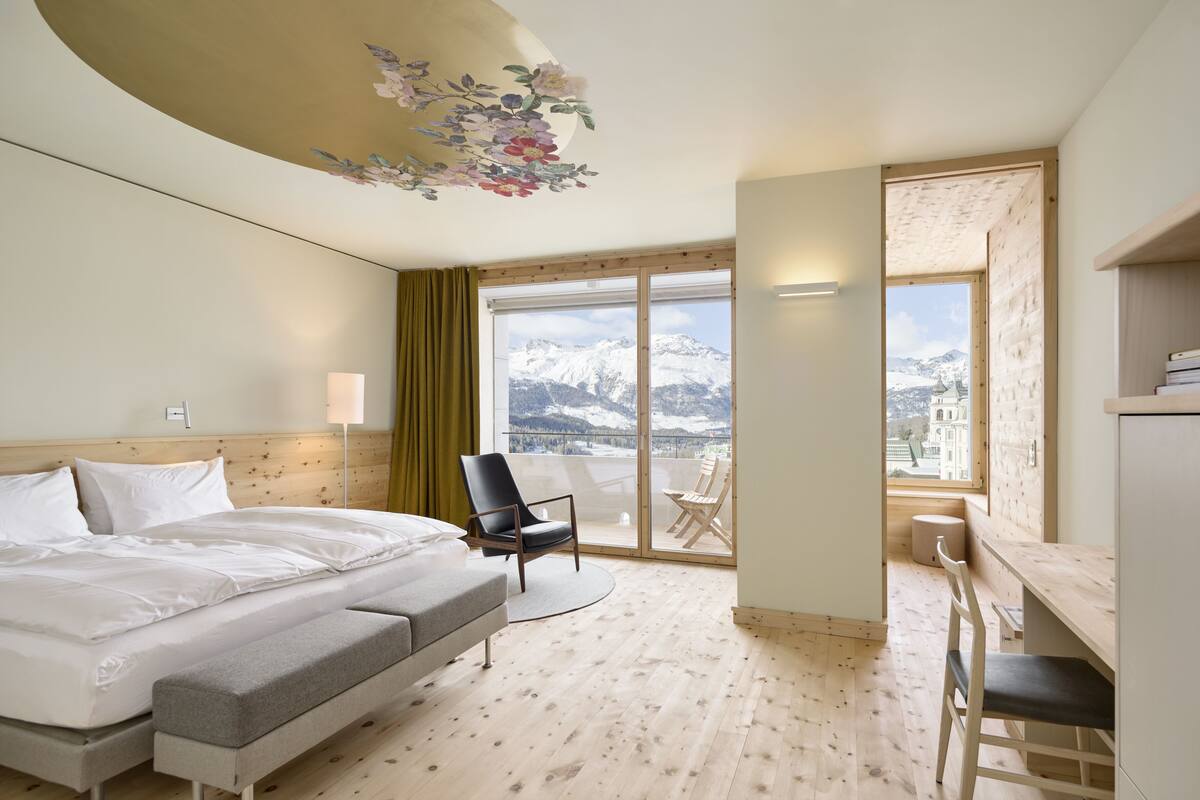 Une chambre d’hôtel avec un lit, un bureau, une chaise et une vue sur les montagnes.