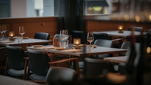 Ein Restaurant mit gedeckten Tischen, Stühlen und Kerzenlicht.