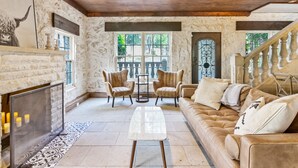 A spacious living room with a fireplace, leather sofa, and a dining area with chairs. - Above Escape LT I Lake Travis I Pool&Spa I Services I Pets (Austin)