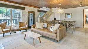 A spacious living area with a high ceiling, a wooden staircase, and a dining area. - Above Escape LT I Lake Travis I Pool&Spa I Services I Pets (Austin)