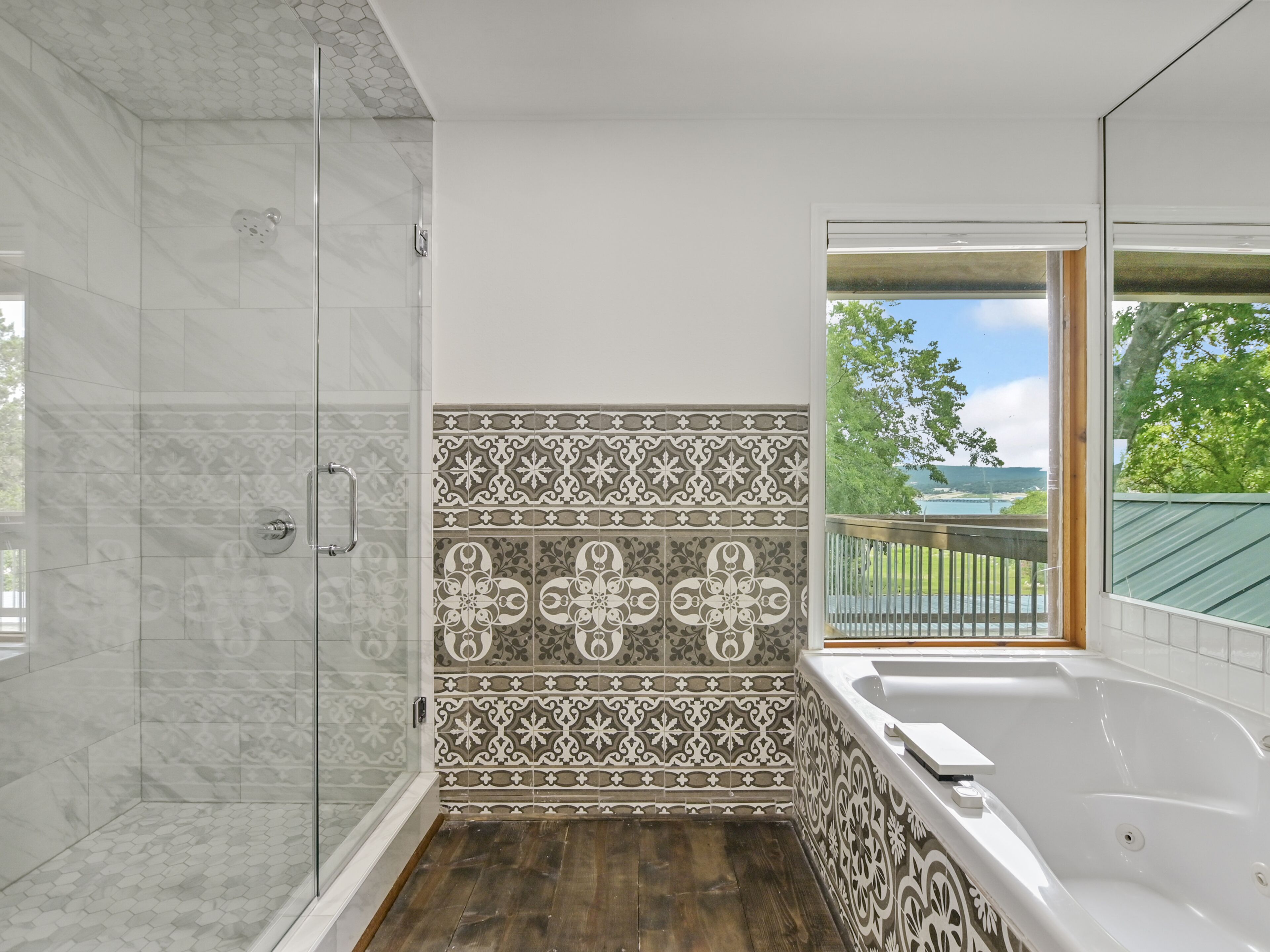 Un baño con ducha, bañera y vistas al exterior.