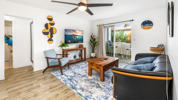 A living room with a ceiling fan, a coffee table, a sofa, and a painting on the wall.