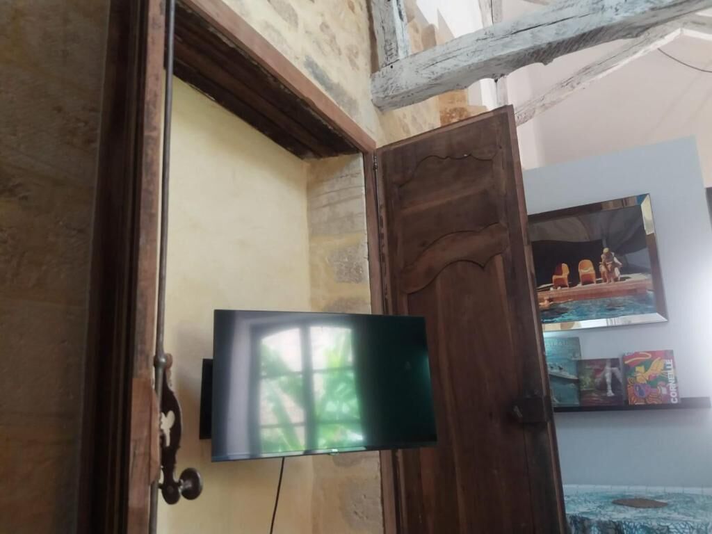 A room with a wooden door, a mounted television, and a framed picture on the wall.