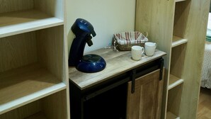 Een kamer met houten kasten, een tafeltje met een blauw voorwerp en een kledingroede.