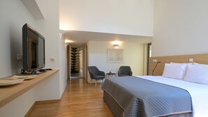 A hotel room with a bed, a TV, a desk, and a chair.