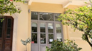 A multi-story building with balconies, large windows, and a door with a metal gate.