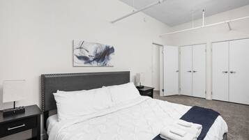 A hotel room with a bed, a nightstand, a lamp, a painting, and a wardrobe.