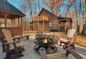 A log cabin with a fire pit and Adirondack chairs in the foreground.