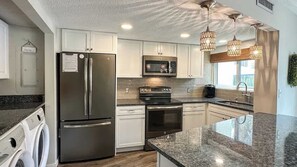 A modern kitchen with stainless steel appliances, granite countertops, and pendant lighting.