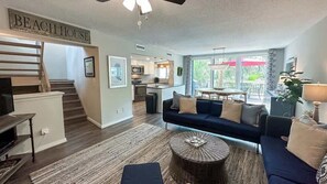 A modern living room with a sofa, coffee table, and a staircase leading to a kitchen.