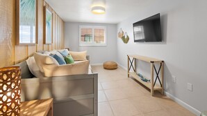 Ein modernes Wohnzimmer mit einer Couch, einem an der Wand befestigten Fernseher und einem Holztischett.