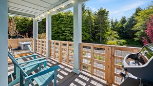 A covered outdoor deck with wooden railings, a grill, and seating areas. - Seabrook White Whale | Hot Tub, Workspace, 3BR | Sleeps 8, South Farm (Pacific Beach)