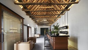Un interior moderno con techos altos, una zona de bar y asientos a lo largo de un pasillo.