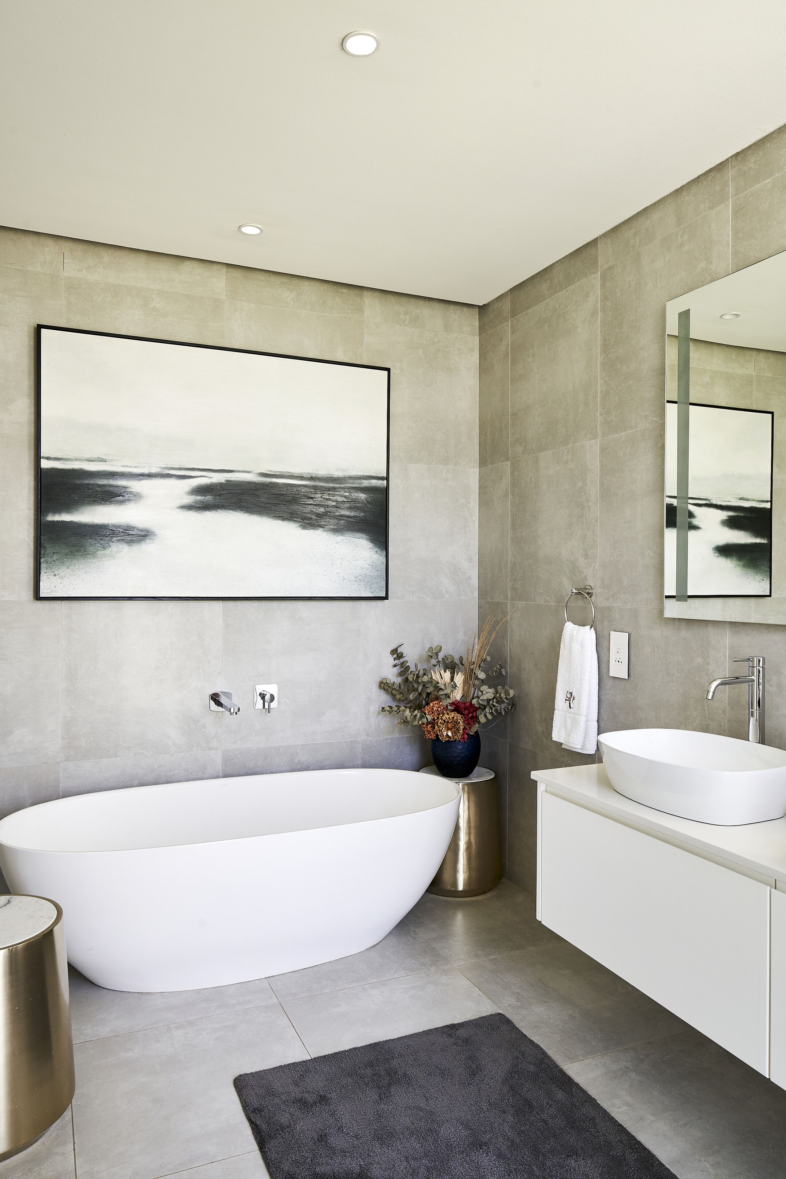 A modern bathroom with a freestanding bathtub, a large mirror, and a wall-mounted sink.