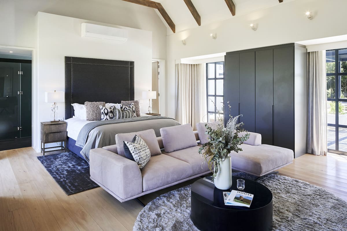Une chambre moderne avec un grand lit, un canapé et une table basse. On y trouve également une armoire et une fenêtre avec des rideaux.
