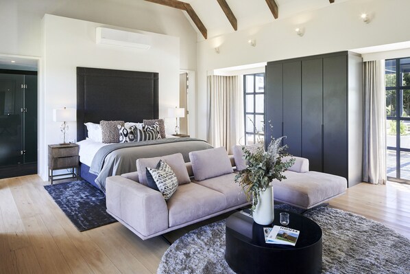 Une chambre moderne avec un grand lit, un canapé et une table basse. On y trouve également une armoire et une fenêtre avec des rideaux.