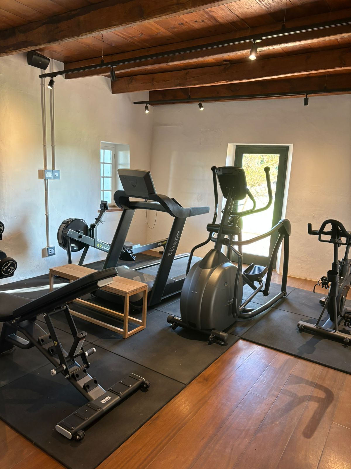 Uma academia em casa com esteira, elíptico e banco de musculação.