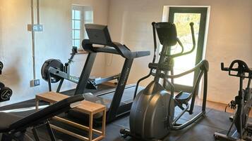 Uma academia em casa com esteira, elíptico e banco de musculação.