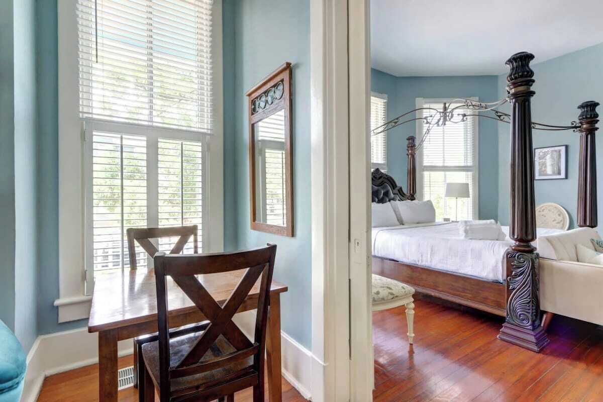A bedroom with a wooden bed, a chandelier, and a large window with blinds.