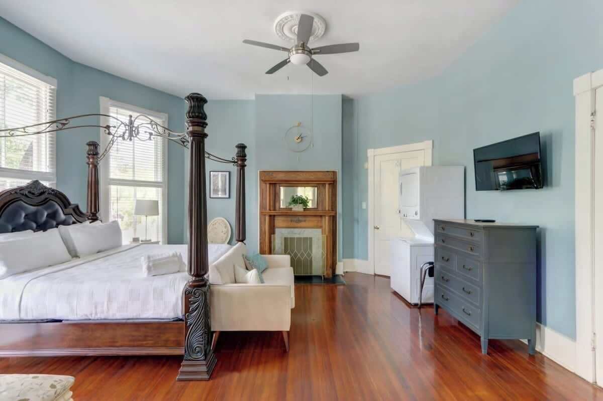 Quarto com cama de dossel, lareira, televisão e cômoda.