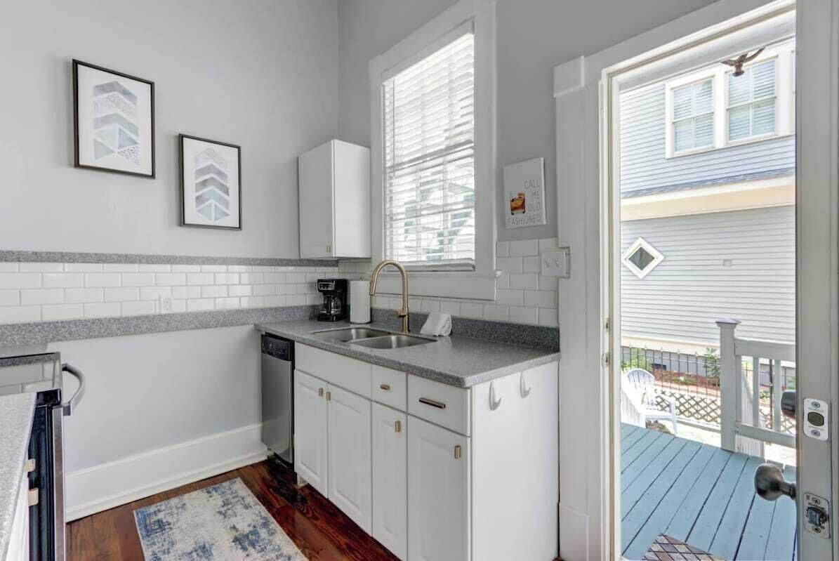 A compact kitchen with white cabinets, a granite countertop, and a built-in dishwasher.