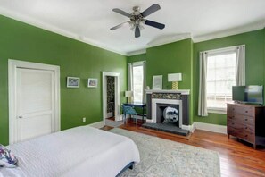 Quarto com cama, lareira, televisão e ventilador de teto.