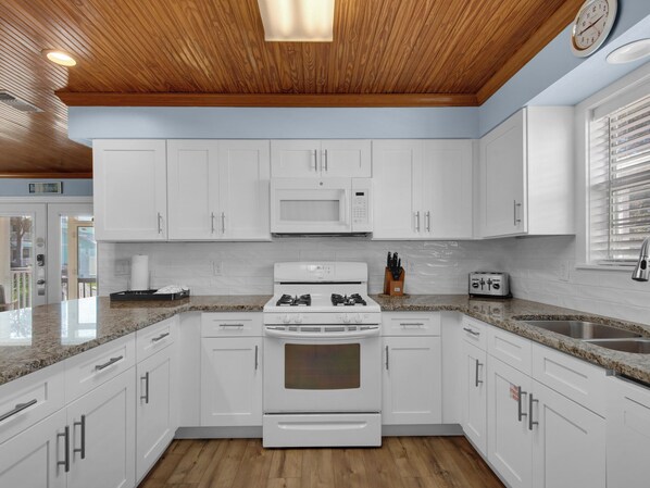 A modern kitchen with white cabinets, a built-in microwave, a gas stove, and a toaster. - Amazing Beach House with Private Pool! (Destin)