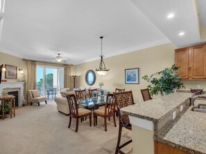 A spacious living room with a dining area, a fireplace, and a large window.