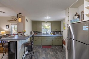 A modern kitchen with a central island, stainless steel appliances, and a view to the outside. - Tristian Suite Walk to Main Street! (Fredericksburg)