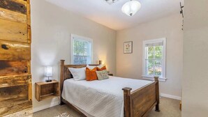 A bedroom with a wooden bed, two bedside tables, a nightstand, and a patterned rug.