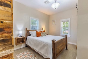 Une chambre à coucher avec un lit en bois, deux tables de chevet, une commode et un tapis à motifs.